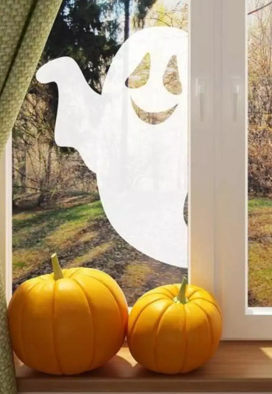 Janela de vidro com adesivo de fantasma. Abóboras também.
