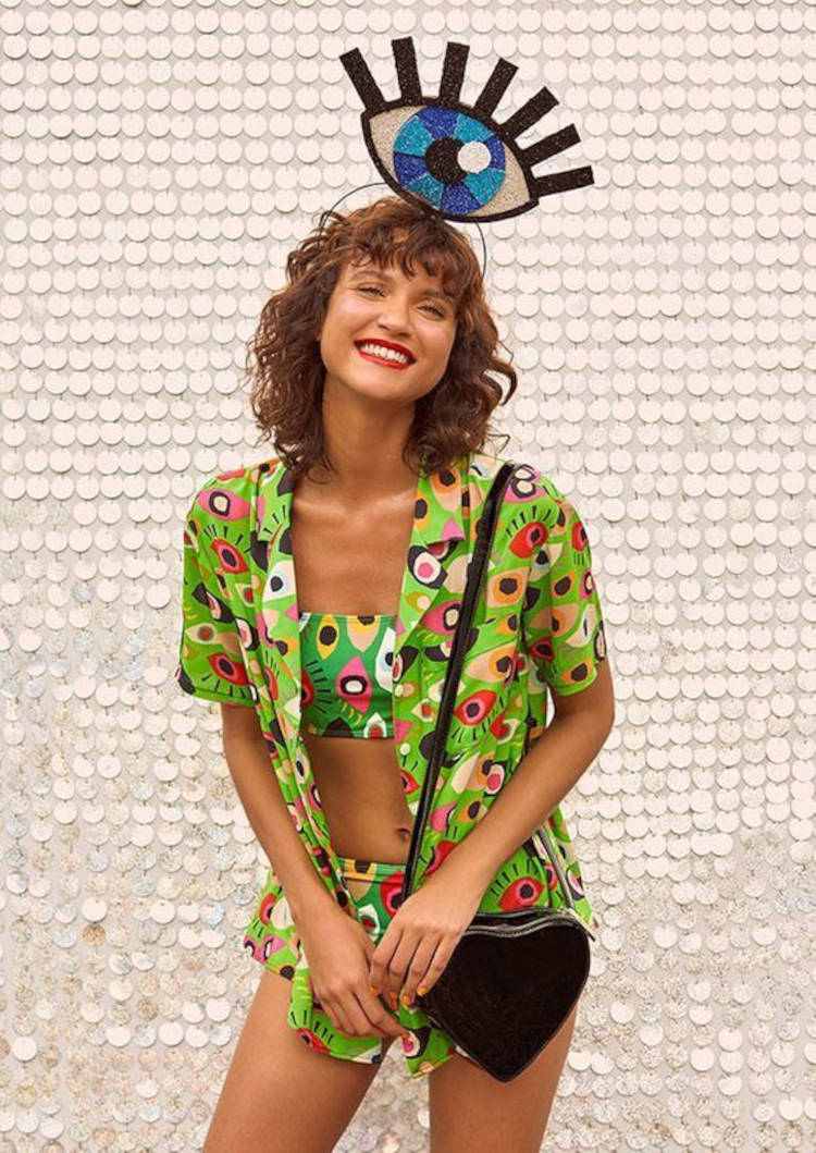 Mulher de pele clara com kimono, top e hot pant verde de olhos e tiara de olho grego