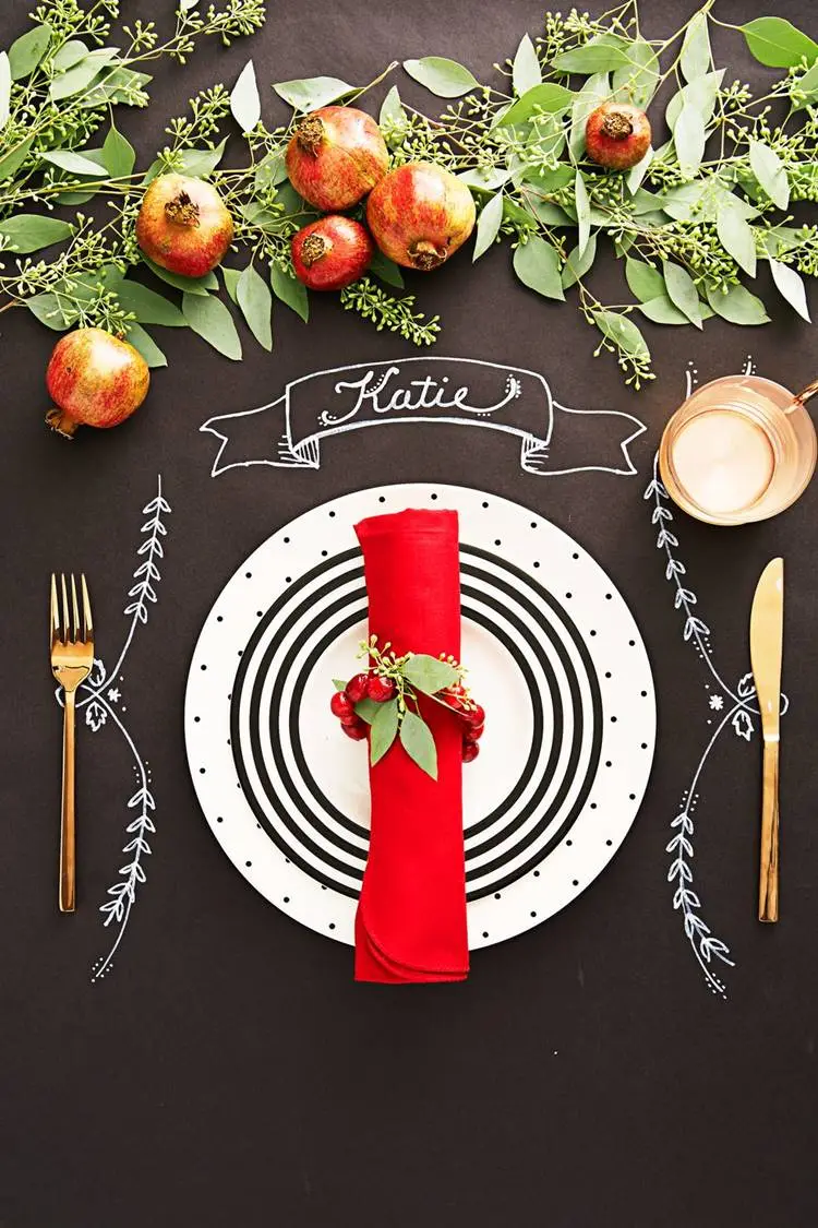 Foto de mesa posta de Natal com papel preto escrito em caneta branca