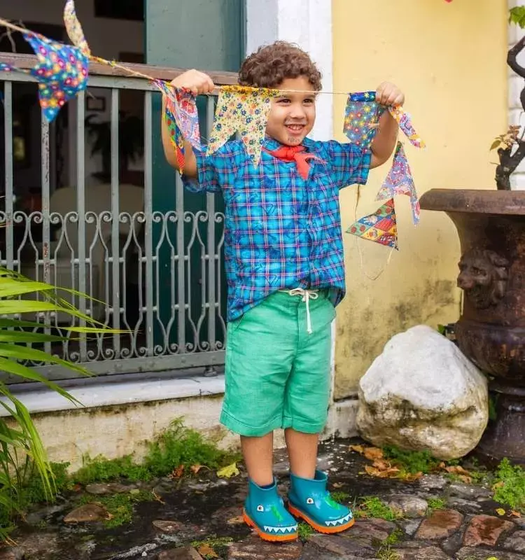 Foto de menino com look para festa quadrilha, com camiseta xadrez azul e bermuda verde