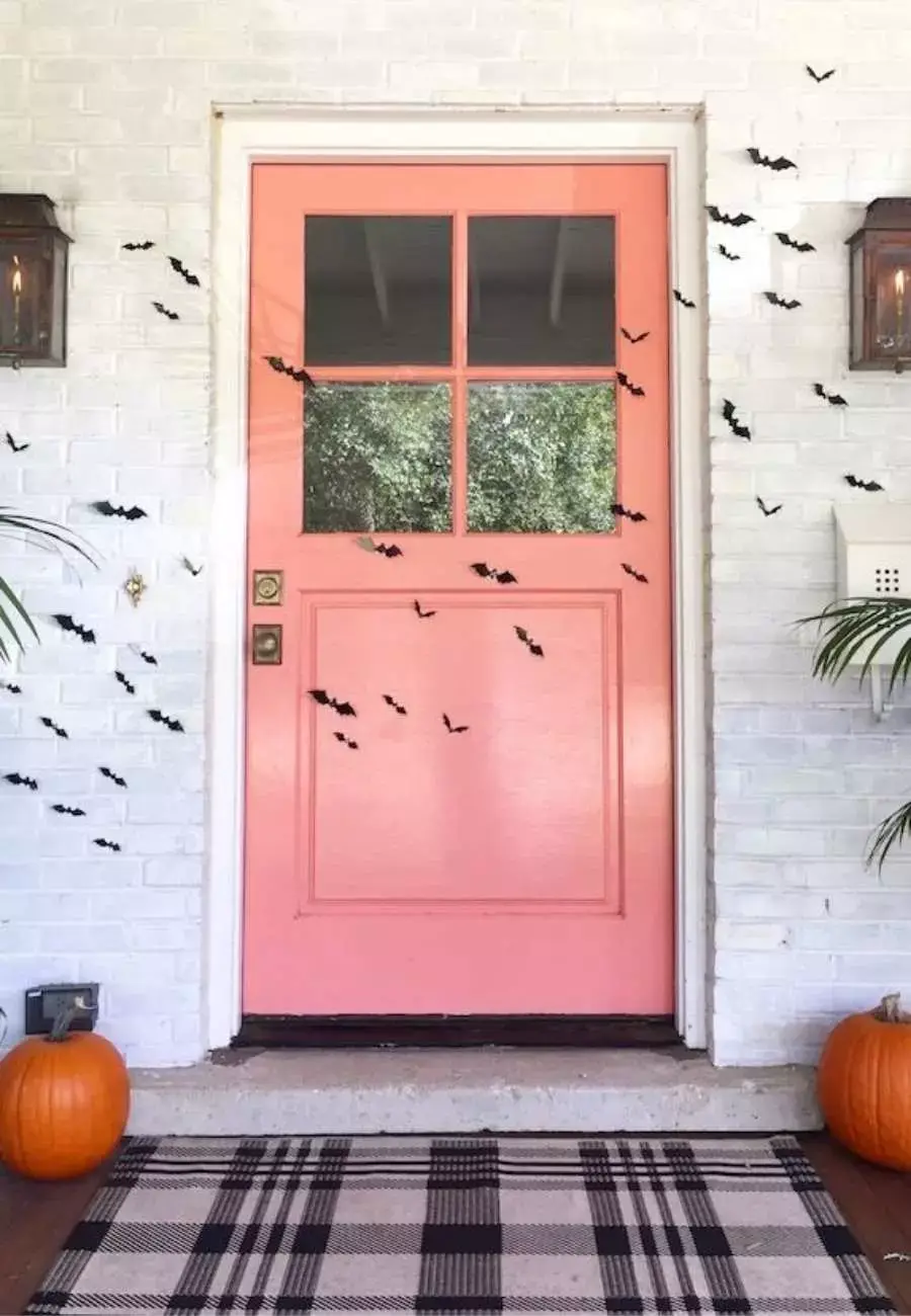 Porta e parede com pequenos morcegos pretos de papel colados.