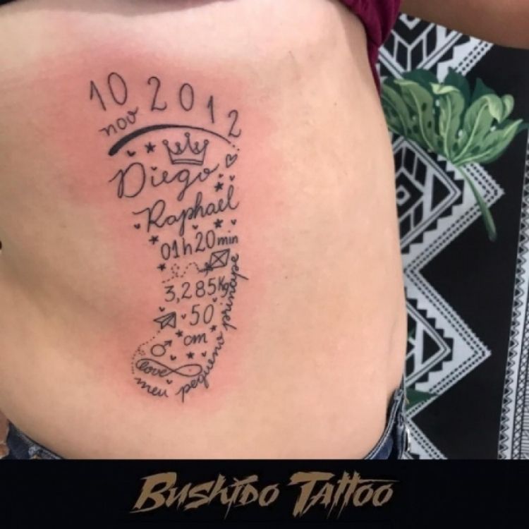 Costela de homem de pele clara com tatuagem de pé com informações de nascimento do filho