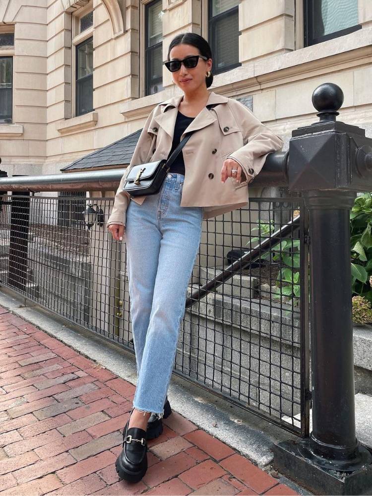 mulher usando blusa preta, jaqueta bege, calça jeans e mocassim preto com fivela