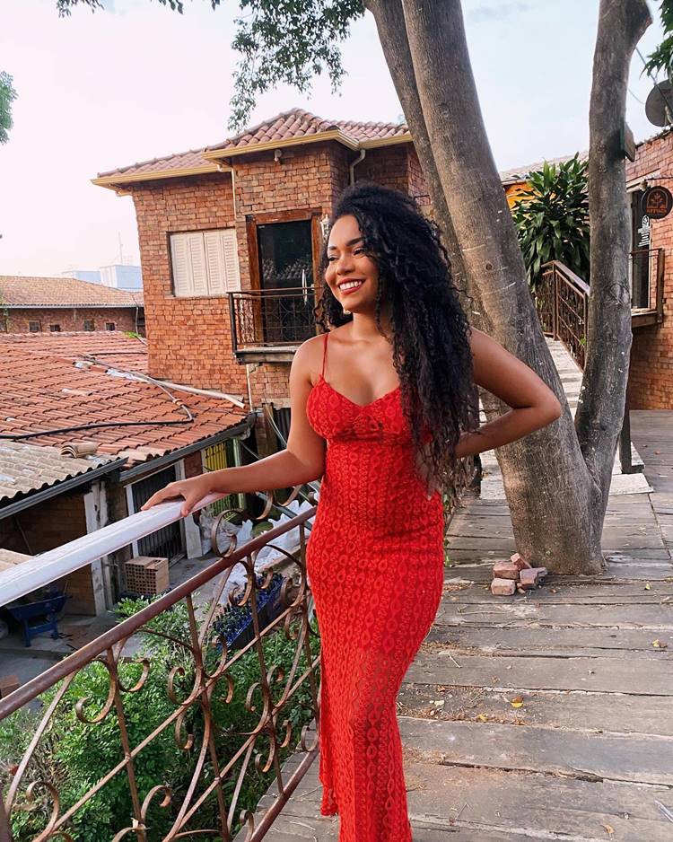 Thalyta Alves do BBB 24 de vestido vermelho em local com árvore e casa de tijolinho