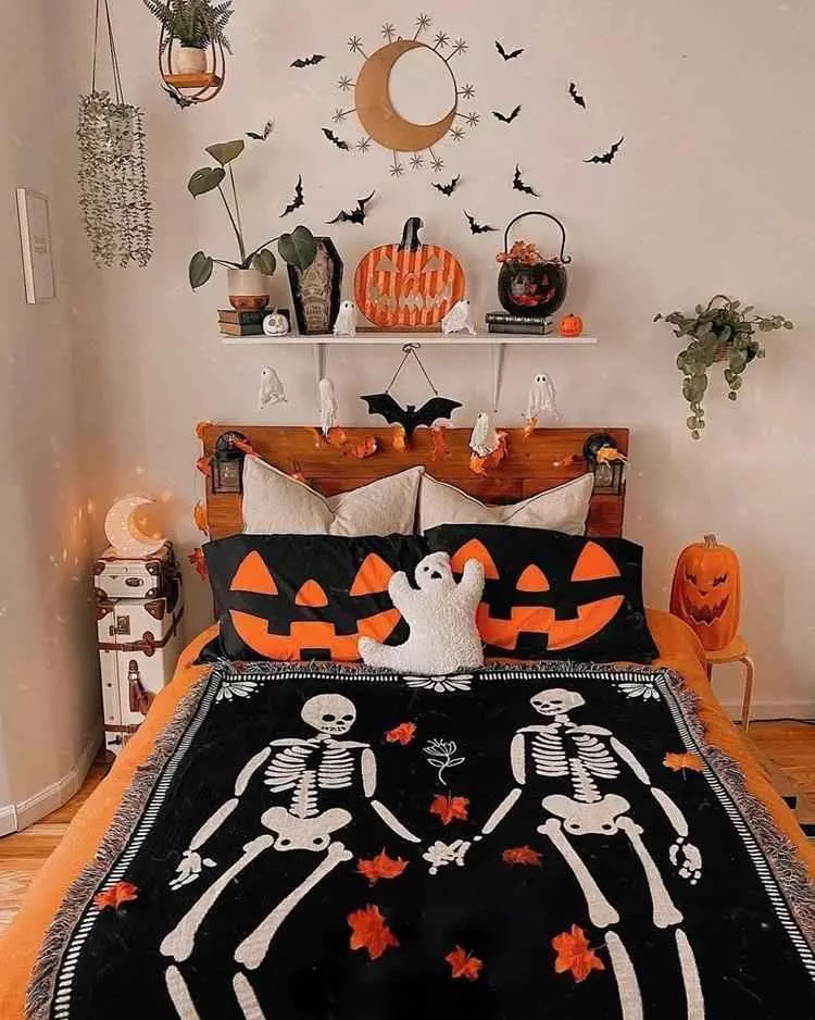 quarto com decoração de halloween, com morcegos de papel, decorações em formato de abóboras, roupa de cama laranja, manta de esqueleto e mais