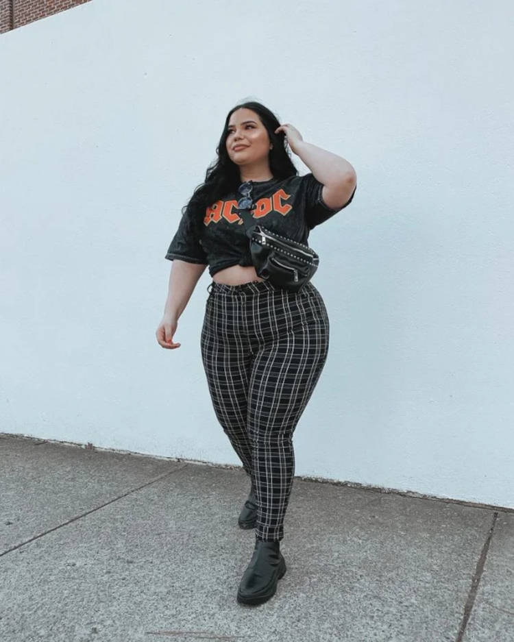 Mulher de pele clara usando camiseta de banda com nózinho e calça xadrez