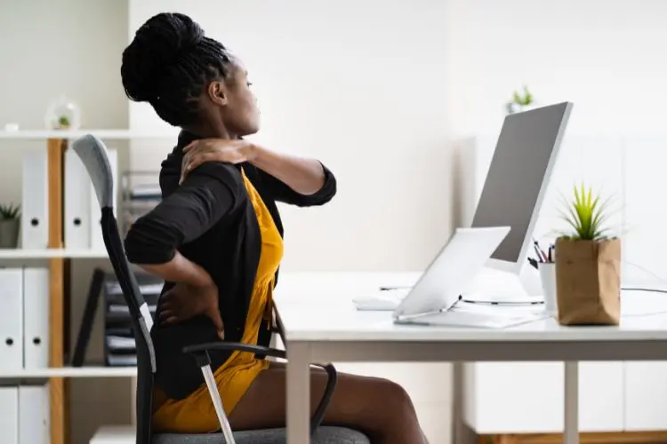 mulher com dor na lombar enquanto trabalha em home office