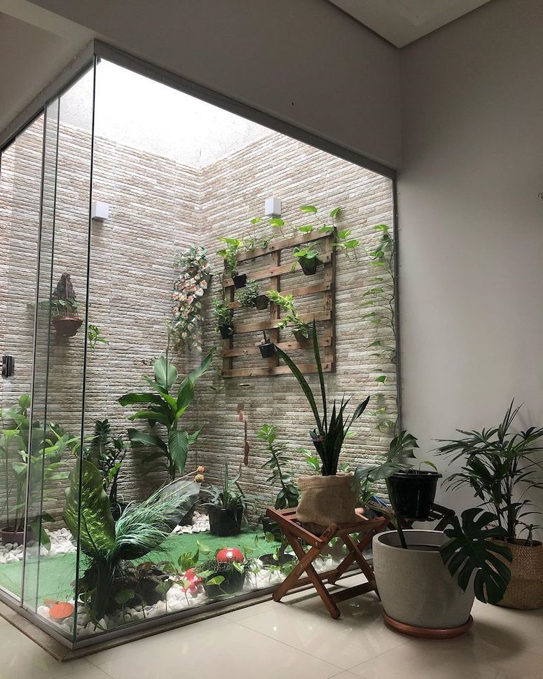 Jardim de inverno de vidro com diversos vasos no chão e suspensos 