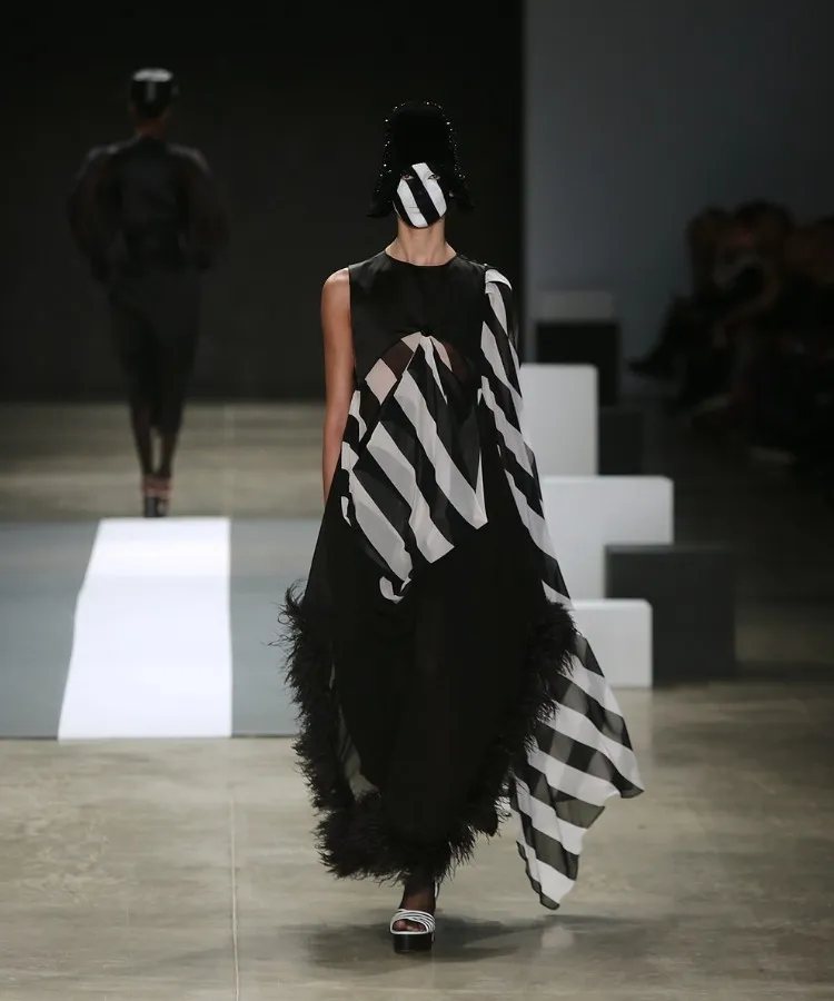 Foto de modelo usando vestido preto com listras brancas no desfile de chapéus de Davi Ramos no SPFW N60