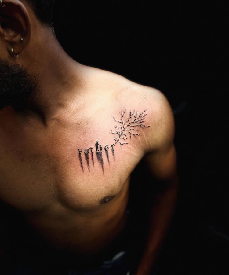 A imagem mostra o torso de um homem com uma tatuagem no peito, no lado direito. A tatuagem representa a palavra "Father" com letras que se transformam em galhos de árvores, estendendo-se em direção ao ombro. O fundo da imagem é escuro, criando um contraste com a pele clara.







