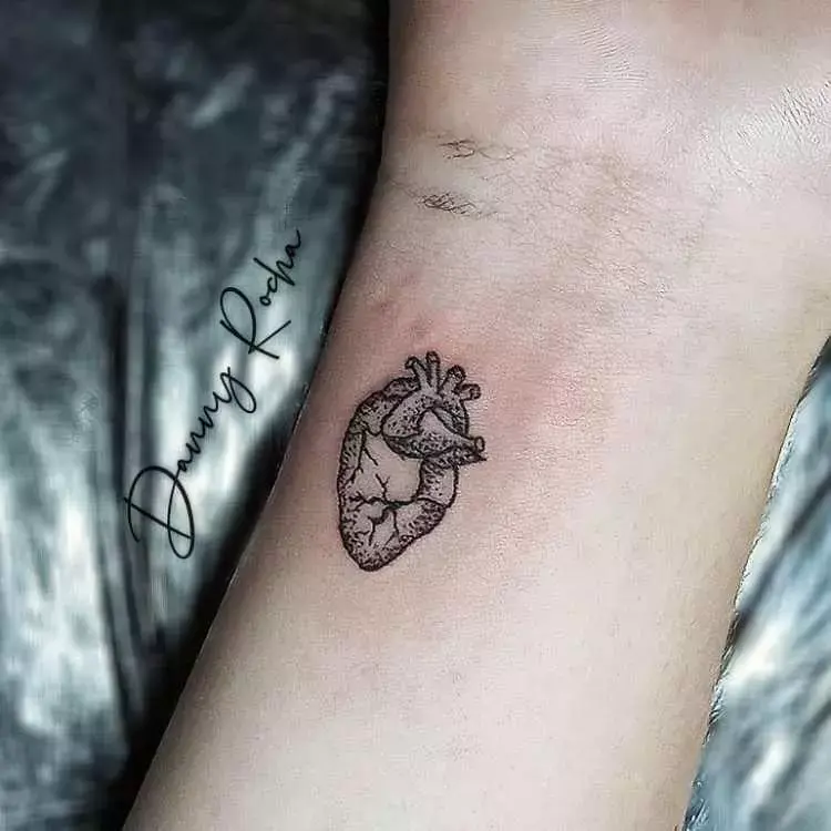 tatuagem de coração na parte de dentro de pulso de pessoa de pele clara 