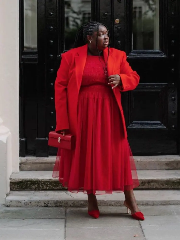 mulher usando vestido de tule vermelho, com blazer, bolsa e scarpin da mesma cor