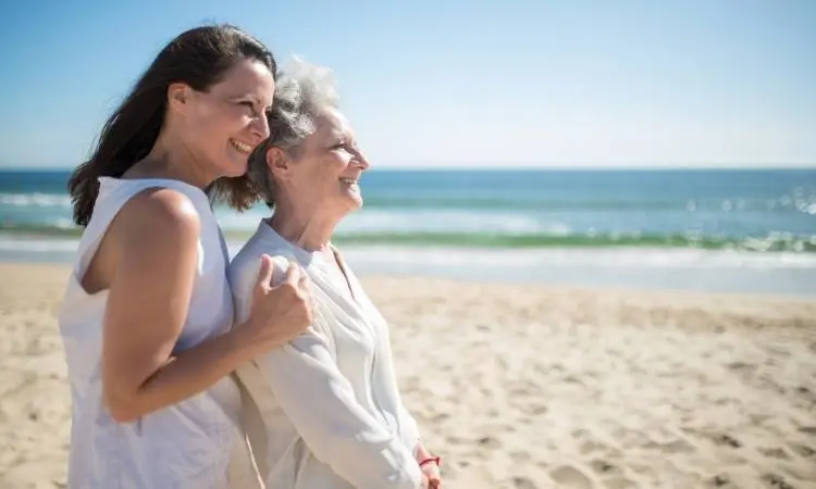 Mãe e filha na praia praticando mindfulness.