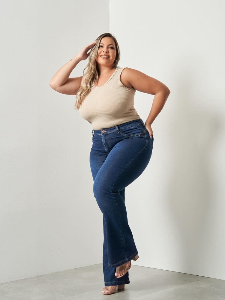 Mulher de pele clara usando regata bege e calça jeans bootcut