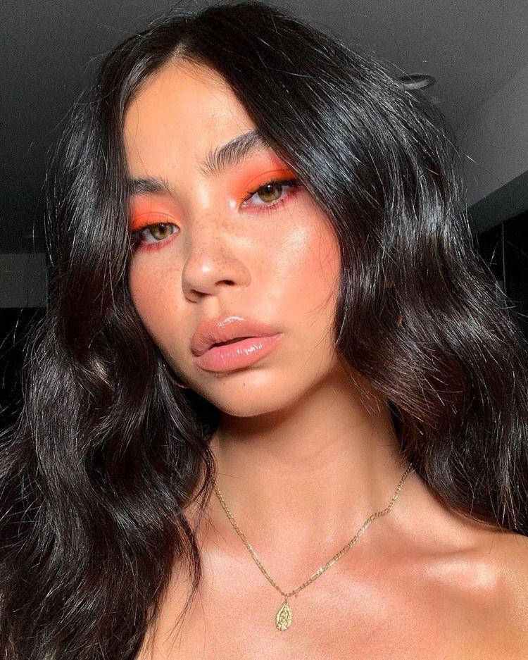 Mulher de descendência asiática usando sombra laranja e pele glow 