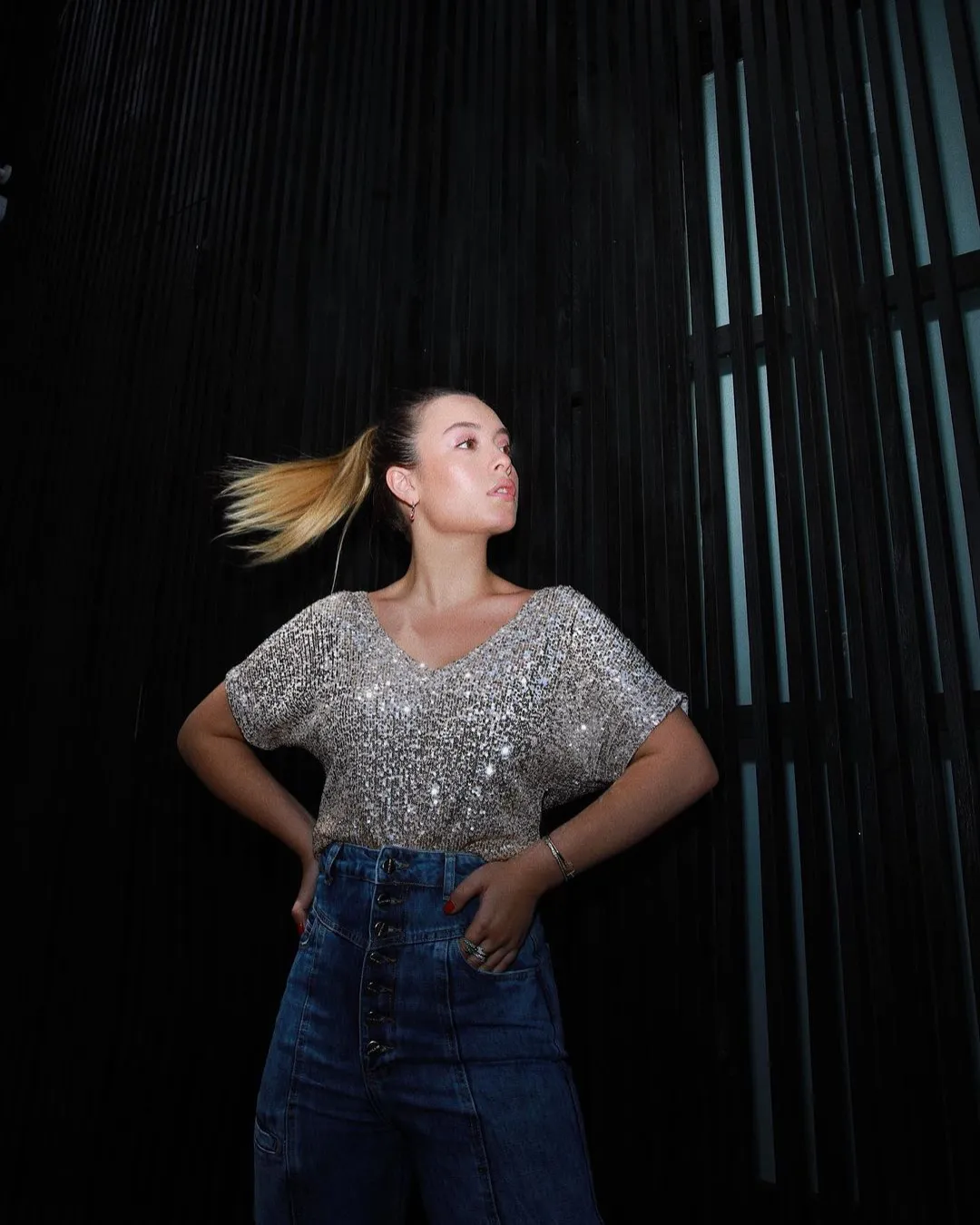 Maria Braz com blusa de paetês prateados e jeans