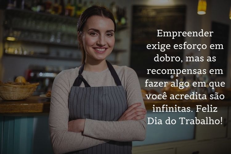 Foto de mulher de pele clara na cozinha usando avental e frase "Empreender exige esforço em dobro, mas as recompensas em fazer algo em que você acredita são infinitas. Feliz Dia do Trabalho!"