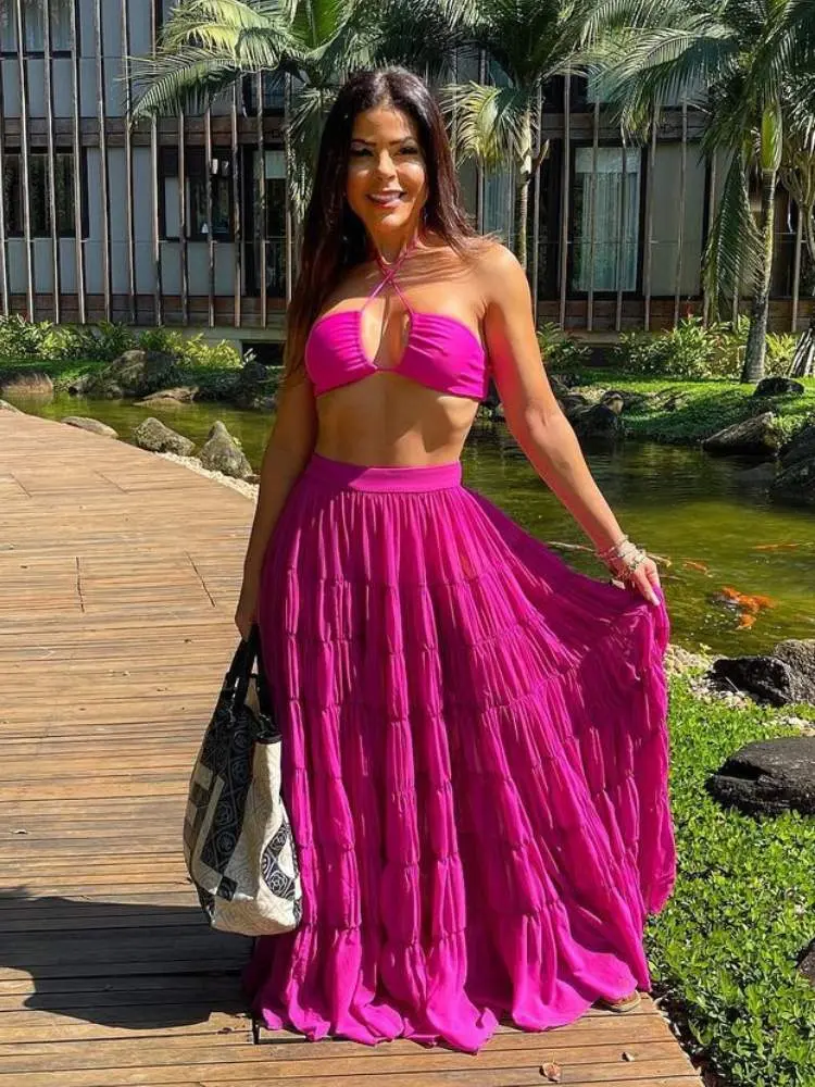 Mulher usa look rosa com biquíni e saia como sugestão de roupa para ano novo na praia