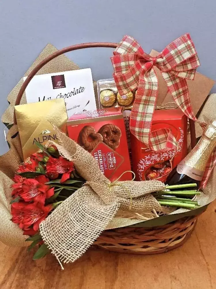 Cesta natalina em tons de vermelho, com laço, bebidas e doces. 