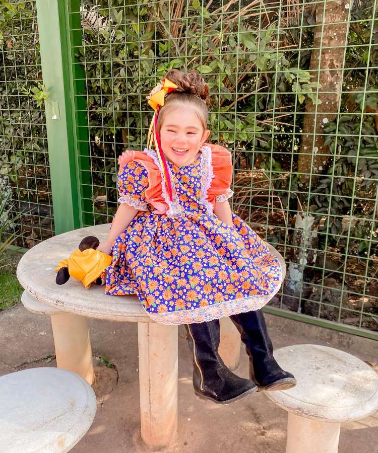Menina com vestido floral azul e laranja e botas pretas para danças quadrilha