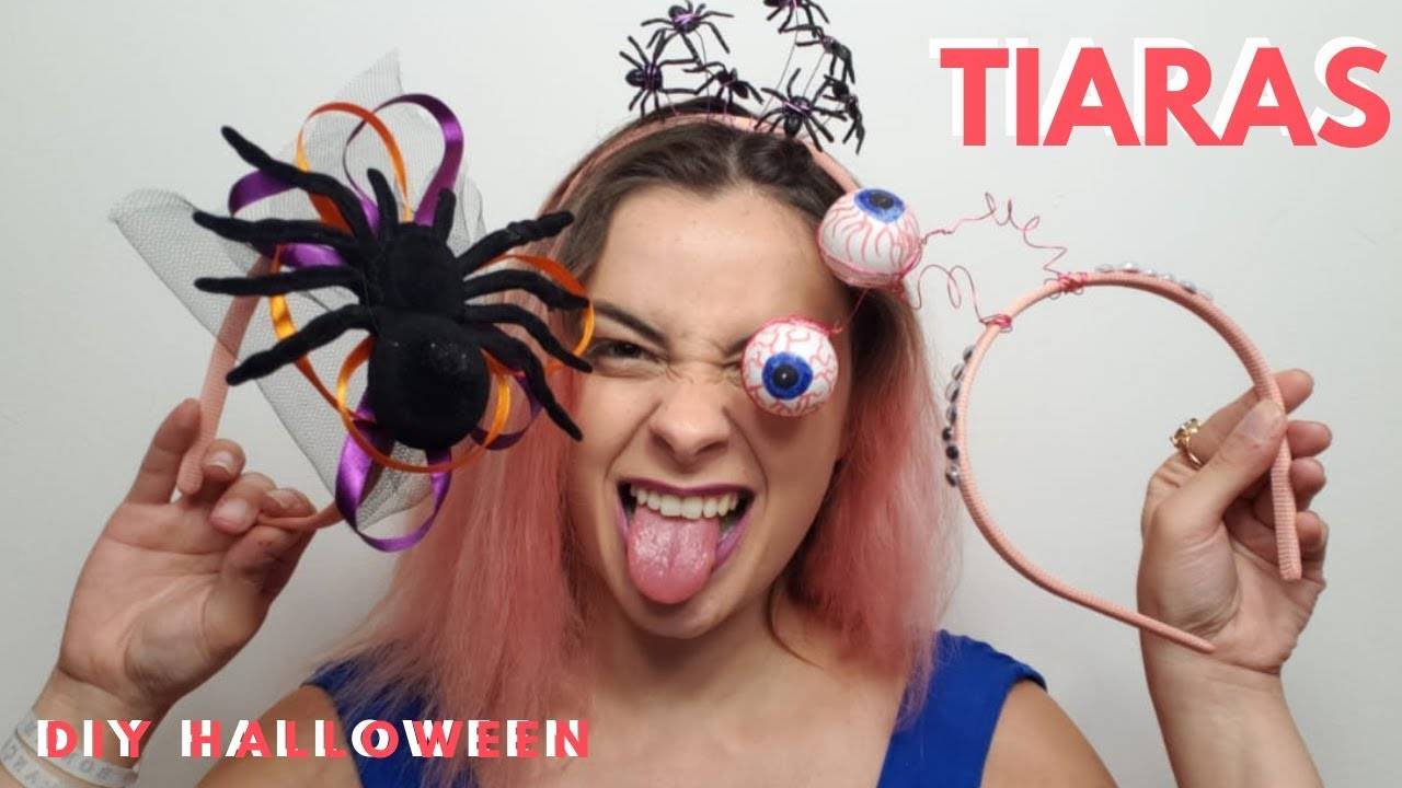 Foto de mulher de pele clara usando tiara com mini aranhas e segurando outras duas tiaras, uma de aranha grande e outra de olhos saltantes