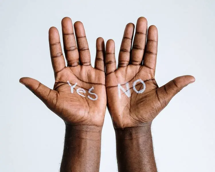 Foto de mão de pessoa com as palavras "Yes" e "No".