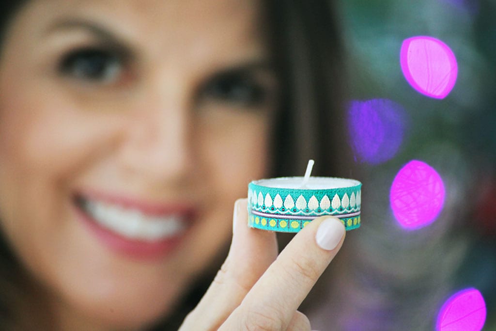 Mulher de pele clara mostrando vela envolta de fita verde