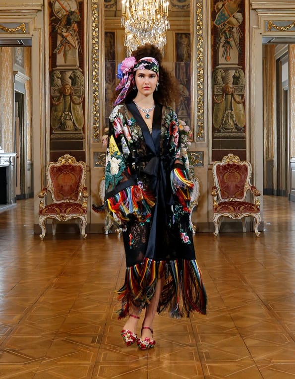 Modelo usando kimono com franjas preto estampado e lenço na cabeça em estética dos anos 20 - Desfile D&G Modelo usando kimono com franjas