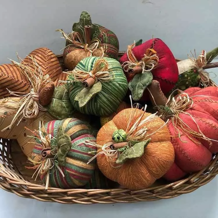 abóboras decorativas, coloridas e em tecido, dentro de cesto de palha