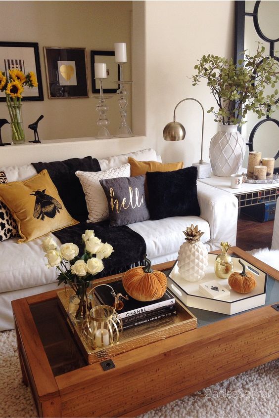 Sala com sofá branco, almofadas estampadas, mesa de centro com decoração de outono