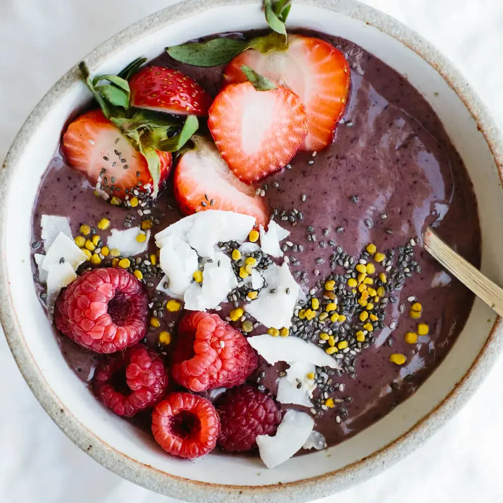 Tigela de açaí com chia, morango, raspas de coco, semente amarela e framboesa