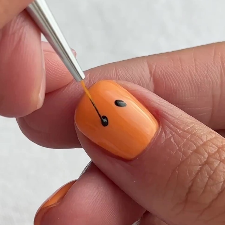 2º passo unha decorada para Halloween carinha de abóbora: fazer olhinhos com pincel e esmalte preto