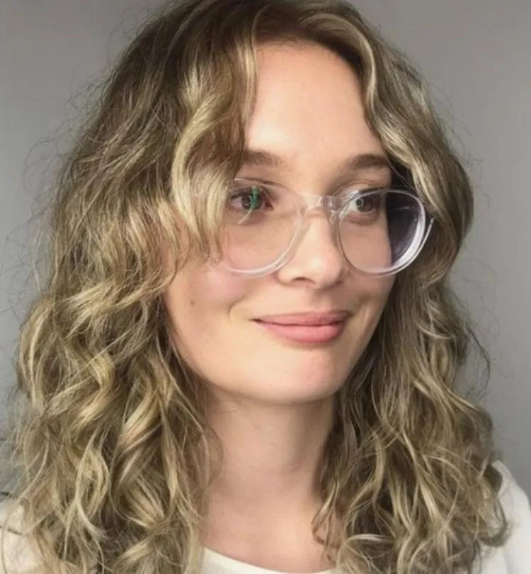 mulher de cabelo médio ondulado loiro e franja média