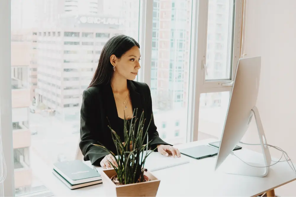 Imagem de mulher em frente ao computador anotando dicas de empreendedorismo feminino no mundo da moda.