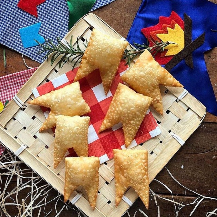 A imagem representa um pastel em formato de bandeirinha como decoração de festa junina