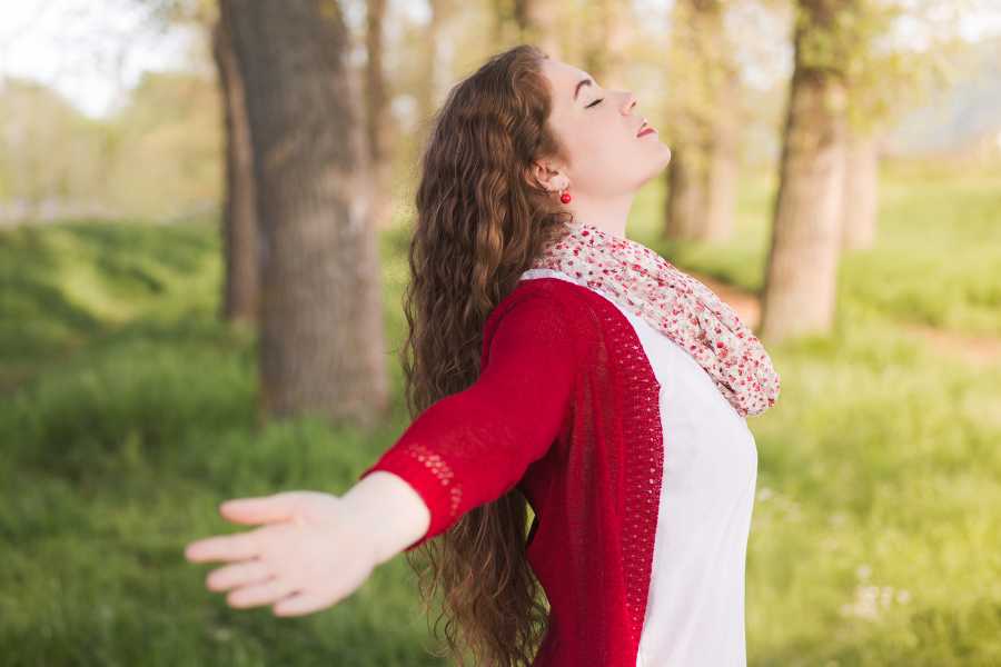 Foto de mulher feliz após praticar reiki ao ar livre.