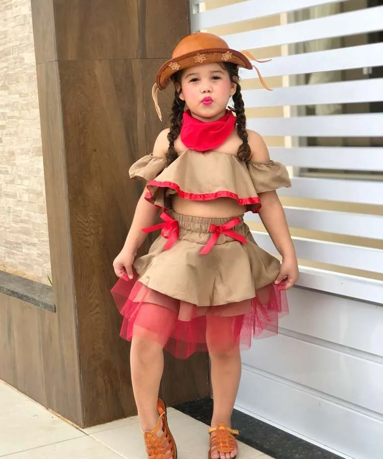 Menina usando look junino country com lenço no pescoço.
