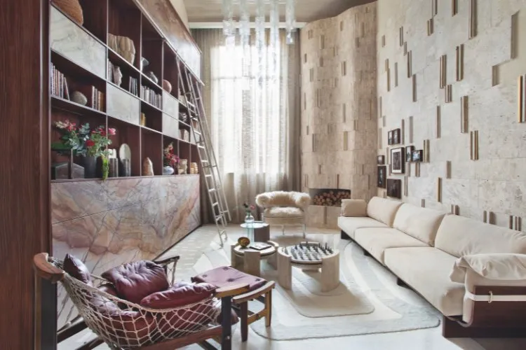 Sala com estante, parede de texturas, poltrona bordô, piso travertino Bahia 