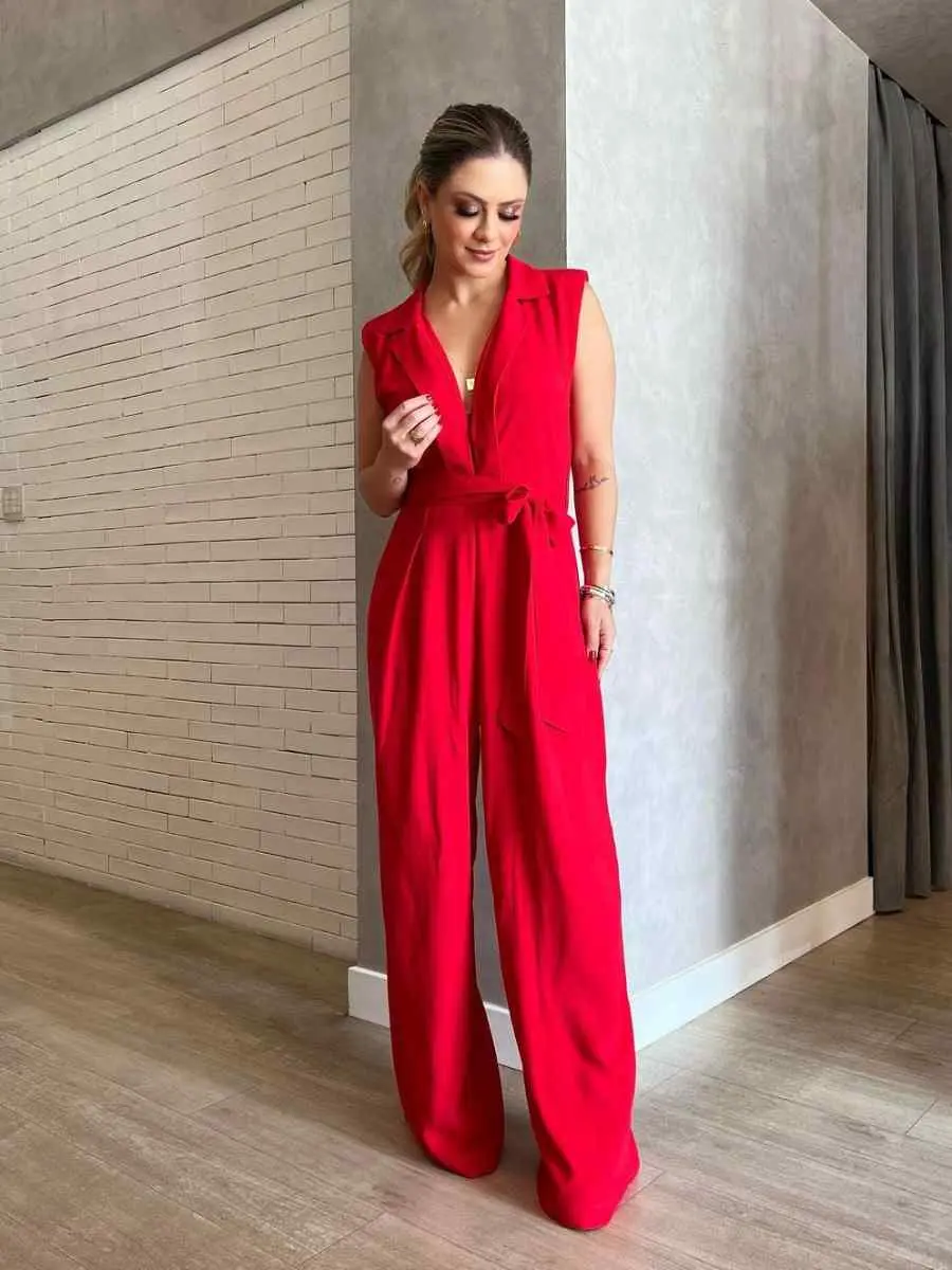 Mulher usando look vermelho para o Natal composto por macacão de alça grossa e laço na cintura
