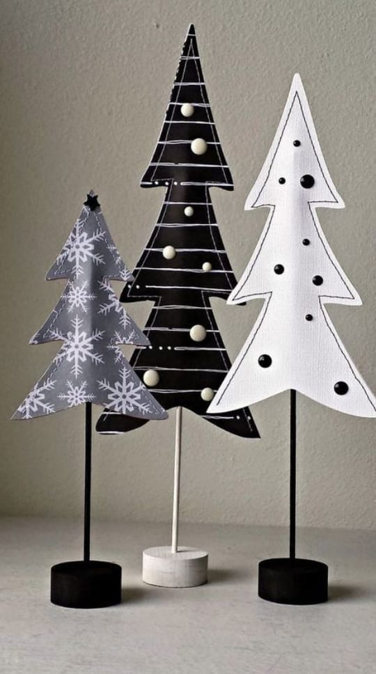 Foto 3pequenas árvores de Natal no palito, sendo uma cinza, uma preta e uma branca
