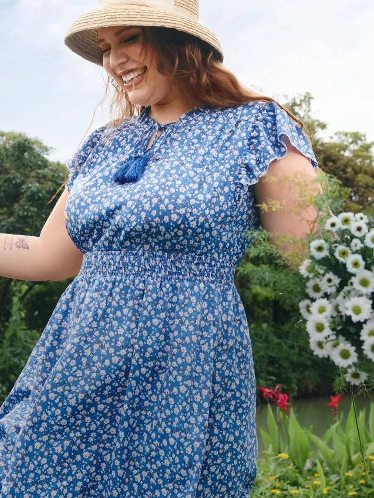 Mulher de pele clara com vestido azul de flores claras bem pequenas 