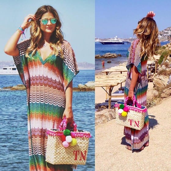 Thássia Naves, famosa, usando vestido longo na praia e com bolsa de palha decorada com pompons.