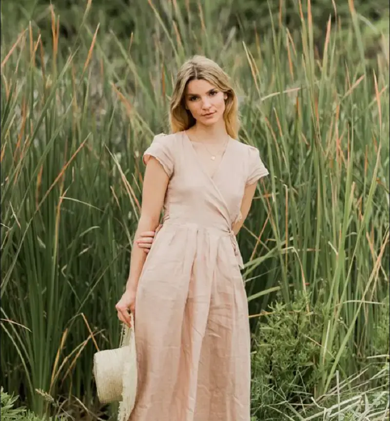 mulher de vestido claro posando no meio de vegetação