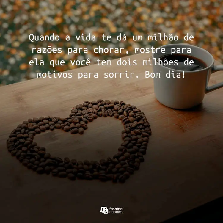Foto de mesa com xícara de café e coração feito com grãos de café, além de frase "Quando a vida te dá um milhão de razões para chorar, mostre para ela que você tem dois milhões de motivos para sorrir. Bom dia!"