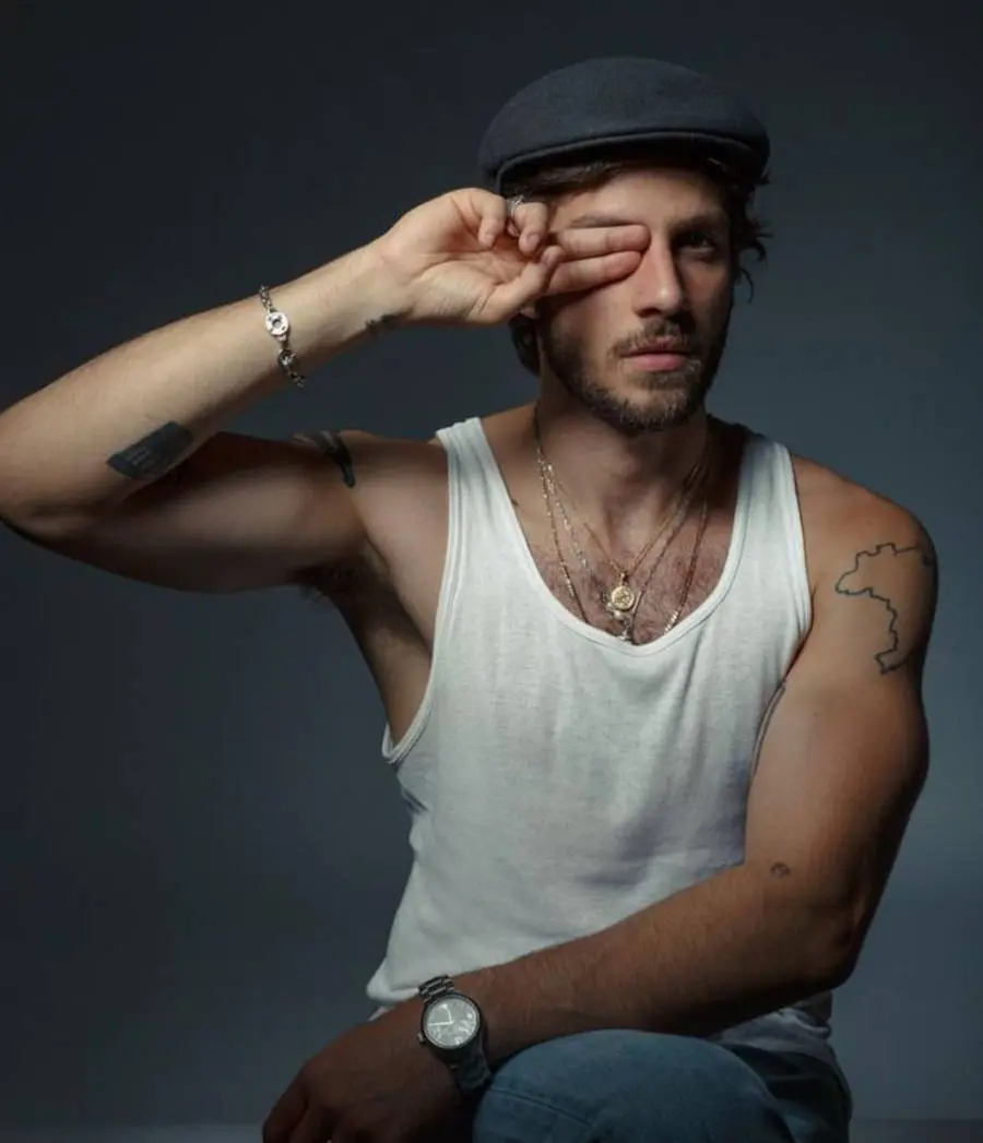 Foto de Chay com o dedo no olho e no antebraço sua tatuagem de cesto de lixo
