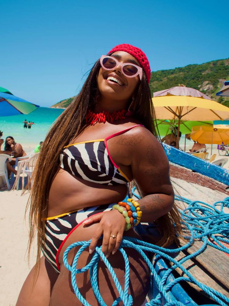 Mari Lobo de biquini de zebra, rede vermelha na cabeça, óculos rosa e pulseiras coloridas