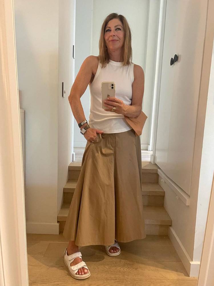 mulher usando regata branca com calça pantacourt marrom e papete branca