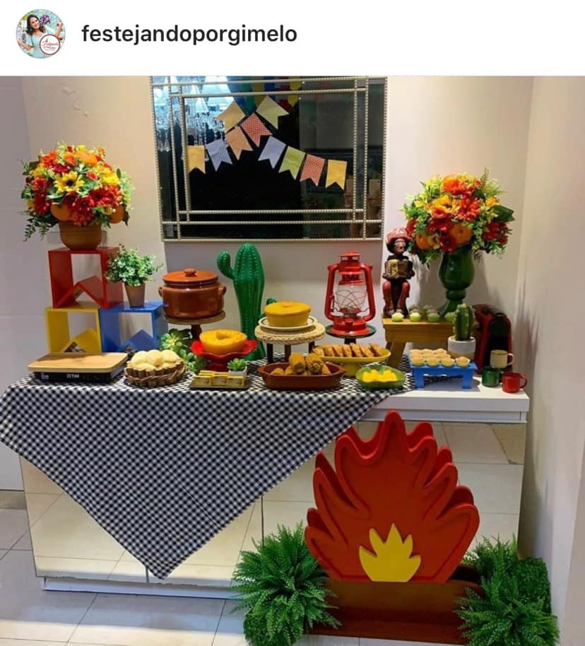 Foto de aparador transformado em mesa de festa junina com comidinhas e decoração de bandeirolas