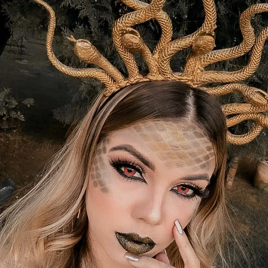 Mulher de pele clara com maquiagem de medusa e tiara dourada de medusa
