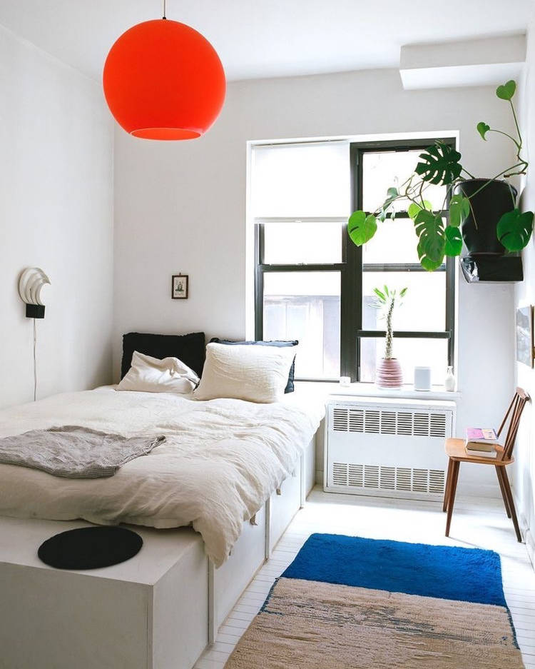 Quarto pequeno decorado com gavetões na cama.